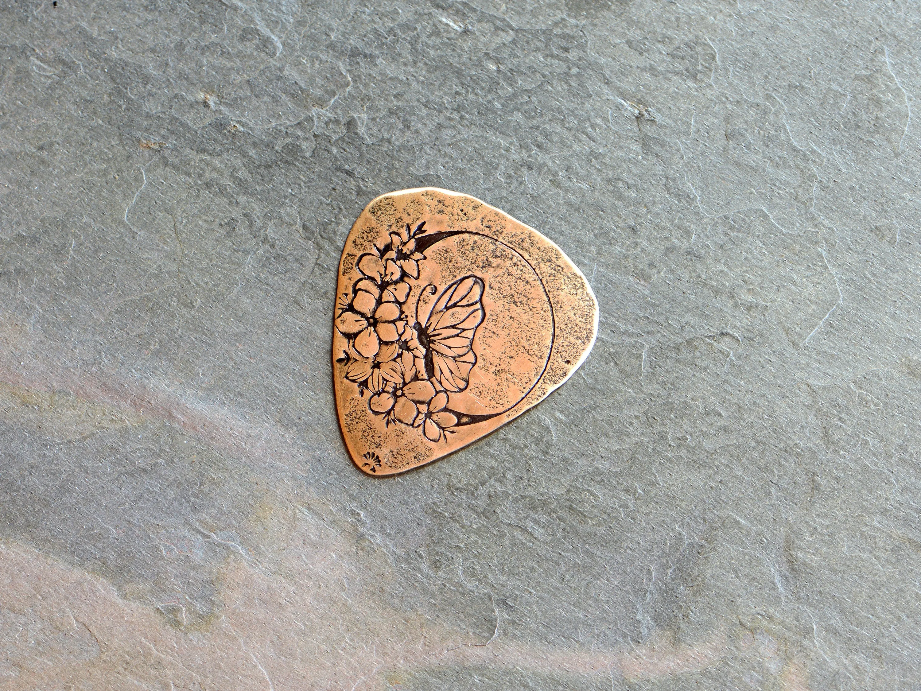 Butterfly moon and flowers on bronze guitar pick